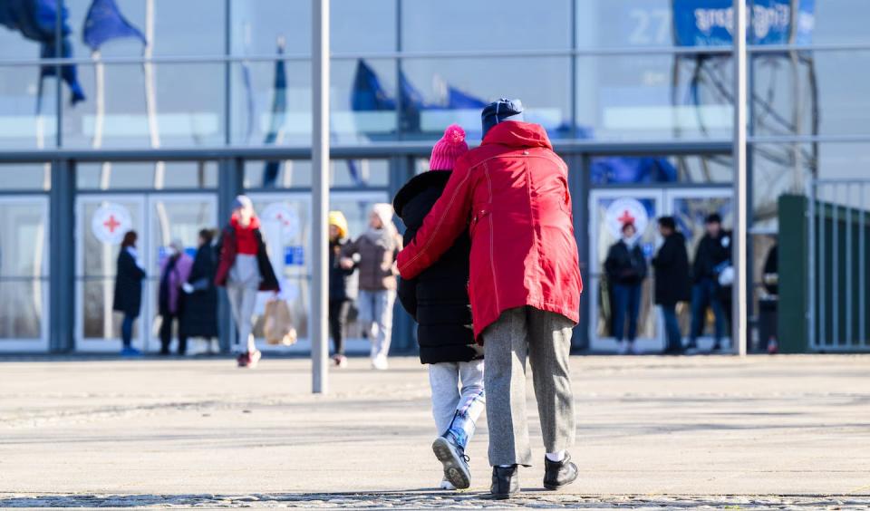 Ukrainians walk toward a refugee shelter set up in an exhibition hall in Dresden, Germany, in March 2022. <a href="https://www.gettyimages.com/detail/news-photo/march-2022-lower-saxony-hanover-a-woman-and-a-child-walk-in-news-photo/1239102319?adppopup=true" rel="nofollow noopener" target="_blank" data-ylk="slk:Julian Stratenschulte/picture alliance via Getty Images;elm:context_link;itc:0;sec:content-canvas" class="link ">Julian Stratenschulte/picture alliance via Getty Images</a>