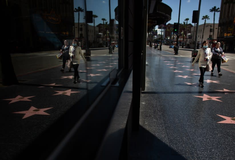 LOS ANGELES, CA - MARCH 26: A women wearing a mask is among the few people on the streets of the Hollywood Walk of Fame during the coronavirus pandemic on Thursday, March 26, 2020 in Los Angeles, CA. (Jason Armond / Los Angeles Times)