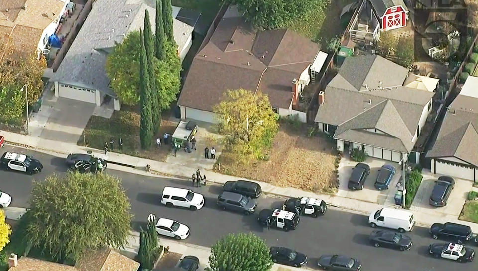 This photo from video provided by KTLA-TV shows police vehicles filling the street in front of the home of the alleged shooter, with the brown roof at center, after a shooting at Saugus High School in Santa Clarita, Calif., early Thursday, Nov. 14, 2019. (KTLA-TV via AP)