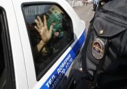 A supporter of members of the female punk band "Pussy Riot" reacts inside a police car after being detained for taking part in an unsanctioned rally outside a court building in Moscow, August 17, 2012.