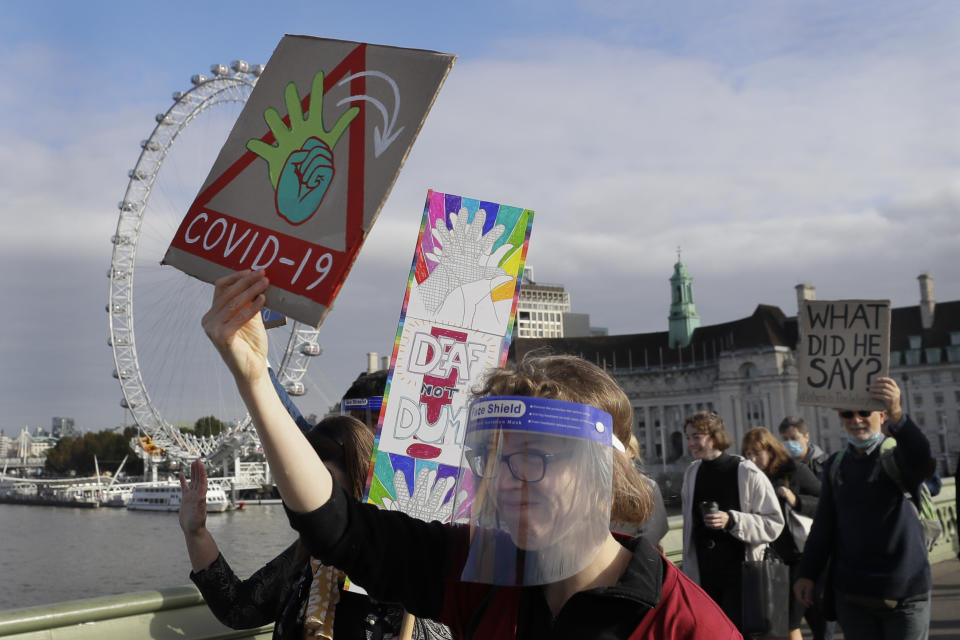 Demonstrators hold banners as they walk over Westminster Bridge in London, Friday, Oct. 16, 2020. Demonstrators supporting the 'Where is The Interpreter' campaign, are asking Britain's Prime Minister Boris Johnson for equal access to communications regarding coronavirus. The campaign is asking the Prime Minister's office to provide a British Sign Language English Interpreter live at televised national addresses during the COVID-19 crisis. (AP Photo/Kirsty Wigglesworth)