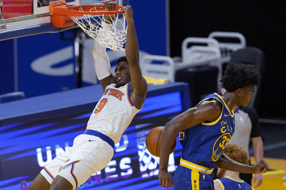 New York Knicks guard RJ Barrett (9) hangs from the rim after dunking next to Golden State Warriors center James Wiseman during the second half of an NBA basketball game in San Francisco, Thursday, Jan. 21, 2021. (AP Photo/Jeff Chiu)