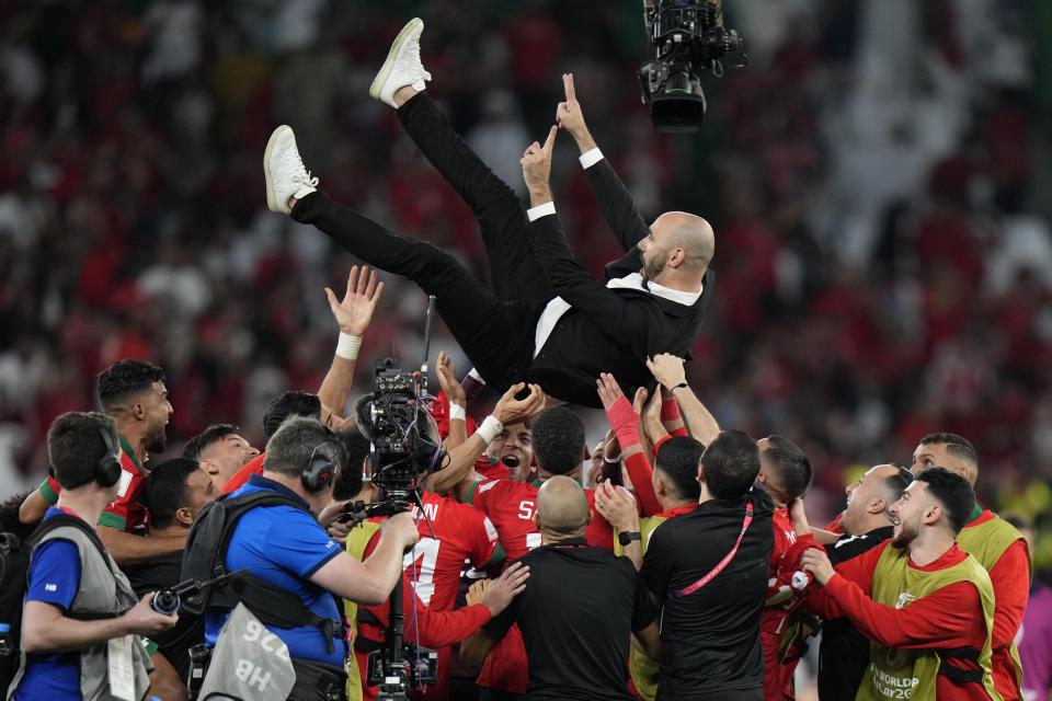 Morocco's players celebrate head coach Walid Regragui after the World Cup round of 16 soccer match between Morocco and Spain, at the Education City Stadium in Al Rayyan, Qatar, Tuesday, Dec. 6, 2022. (AP Photo/Luca Bruno)