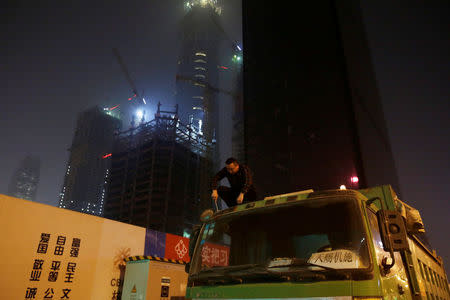 A driver repairs on the top of a truck next to construction sites at night in Beijing's central business district area, China April 16, 2017. REUTERS/Jason Lee