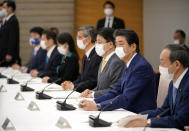 Japanese Prime Minister Shinzo Abe, second right, declares a state of emergency during a meeting of the task force against the coronavirus at the his official residence in Tokyo, Tuesday, April 7, 2020. Abe declared a state of emergency for Tokyo and six other prefectures to ramp up defenses against the spread of the coronavirus. (Franck Robichon/Pool Photo via AP)