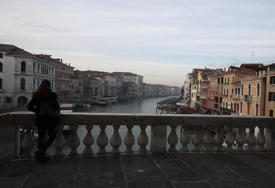 FILE - In this Jan. 30, 2021 file photo, a woman looks the Canal Grande or Grand Canal, in Venice, Italy. The canal city's Carnival festivities should have started on Jan. 30, but the COVID-19 pandemic made the annual appointment for more than two weeks of merry-making impossible. Venice’s central place in the history of battling pandemics and pestilence will come into focus at this year’s Venice Film Festival, which opens Wednesday with the premiere of Pedro Almodovar’s in-competition “Madres Paralelas” (Parallel Mothers), which he developed during Spain’s 2020 coronavirus lockdown, one of the harshest in the West. (AP Photo/Antonio Calanni)