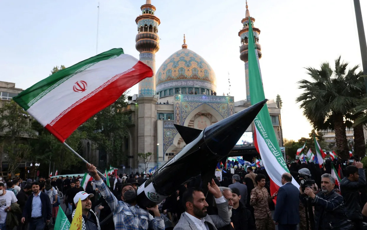 Iranians carry a model of a missile during a celebration following the IRGC attack on Israel