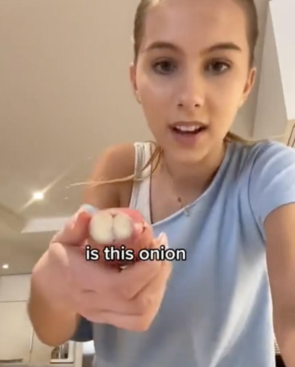 Romy holds up garlic while asking if it's an onion