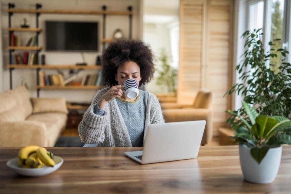 Woman drinking from cup at kitchen table.