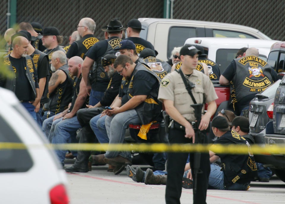 FILE - In this May 17, 2015 file photo, a McLennan County deputy stands guard near a group of bikers in the parking lot of the Twin Peaks restaurant in Waco, Texas. An attorney for six men arrested after the 2015 shootout between rival biker gangs that left nine people dead and at least 20 injured asked a district court judge Wednesday, June 5, 2019, to assign a special master to supervise the return of items seized from the nearly 200 detained bikers. (Rod Aydelotte/Waco Tribune-Herald via AP, File)