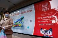 Woman stands near an Alibaba's advertisement promoting Singles Day shopping festival in Beijing