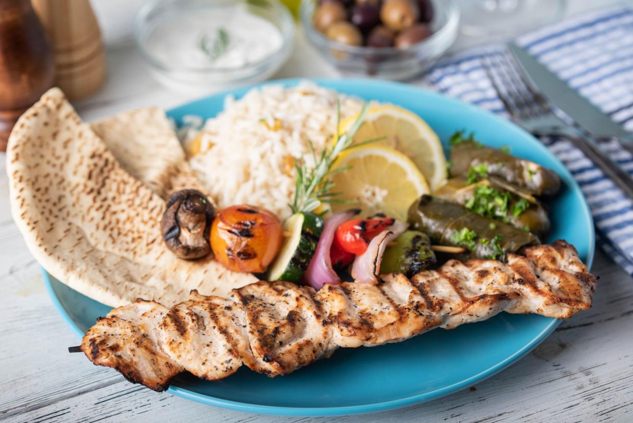 assorted greek food platter with souvlaki, rice, pita and dolmades