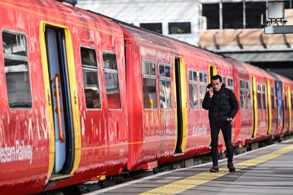 A commuter walks past a train stopped at a platform in Waterloo Station in London. (Photo by JUSTIN TALLIS/AFP via Getty Images)