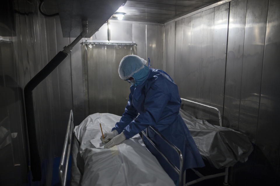 A healthcare worker fills out paper work for a patient who died from COVID-19, in a morgue at the Samaritana Hospital in Bogota, Colombia, Thursday, June 3, 2021. Colombia has become a pandemic hotspot experiencing a third wave of COVID-19 infections and a surge in deaths. (AP Photo/Ivan Valencia)