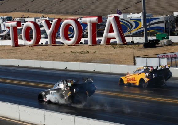 Drag race with two cars in front of a Toyota sign.