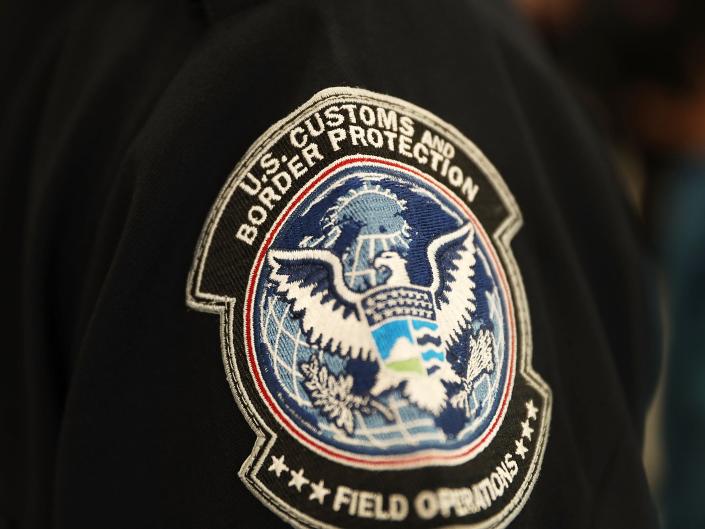 یک وصله روی آستین یک افسر گمرک و حفاظت مرزی ایالات متحده دیده می شود که او از فناوری تشخیص چهره در غرفه خود در فرودگاه بین المللی میامی برای غربالگری مسافری که در 27 فوریه 2018 وارد ایالات متحده می شود در میامی، فلوریدا استفاده می کند.