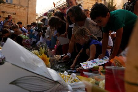 Children place flowers, candles and drawings at a memorial for murdered investigative journalist Daphne Caruana Galizia, who was killed by a car bomb last Monday, in Valletta, Malta, October 22, 2017. REUTERS/Darrin Zammit Lupi