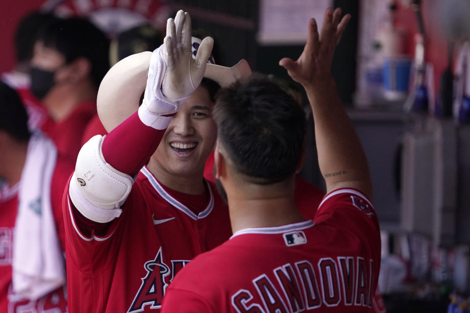 Los Angeles Angels' Shohei Ohtani, left, celebrates in the dugout with starting pitcher Patrick Sandoval after hitting a solo home run during the first inning of a baseball game against the Oakland Athletics Sunday, May 22, 2022, in Anaheim, Calif. (AP Photo/Mark J. Terrill)