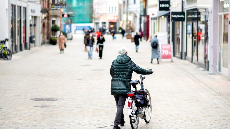 Eine Frau schiebt ihr Fahrrad durch die wenig belebte Fußgängerzone in Oldenburg. Angesichts stark steigender Infektionszahlen wird der Lockdown in Deutschland verlängert.