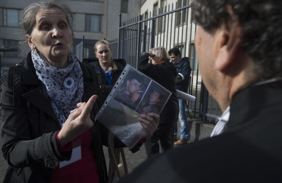 A woman with the Mothers of Srebrenica, holds the photographs of two victims of the Bosnian war as she talks to Peter Robinson of the U.S., lawyer for former Bosnian Serb leader Radovan Karadzic, right, after the court upheld Karadzic's conviction at International Residual Mechanism for Criminal Tribunals in The Hague, Netherlands, Wednesday, March 20, 2019. Nearly a quarter of a century since Bosnia's devastating war ended, Karadzic heard the final judgment upholding 2016 convictions for genocide, crimes against humanity and war crimes, and an increase from his 40-year sentence to life. (AP Photo/Peter Dejongl)