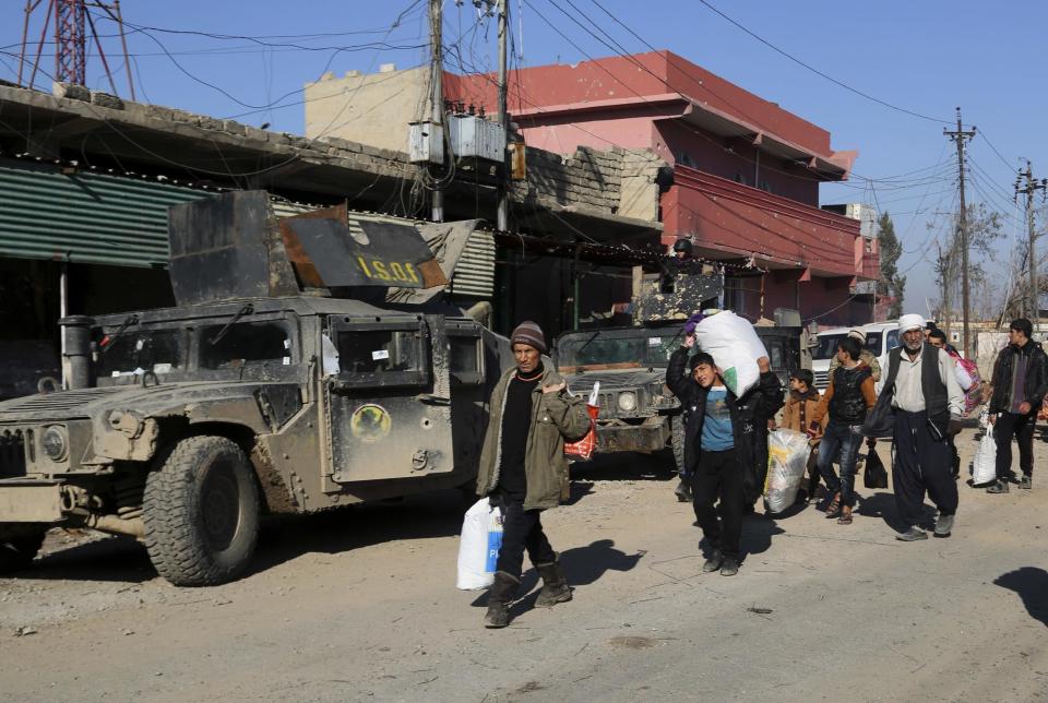 Residents bring food to their families after being trapped for days in their homes due to fighting between Iraqi security forces and Islamic State militants, in Mosul, Iraq, Monday, Jan. 2, 2017. (AP Photo/ Khalid Mohammed)