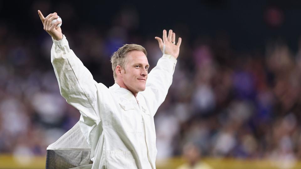 A beekeeper waves to the MLB crowd after clearing bees