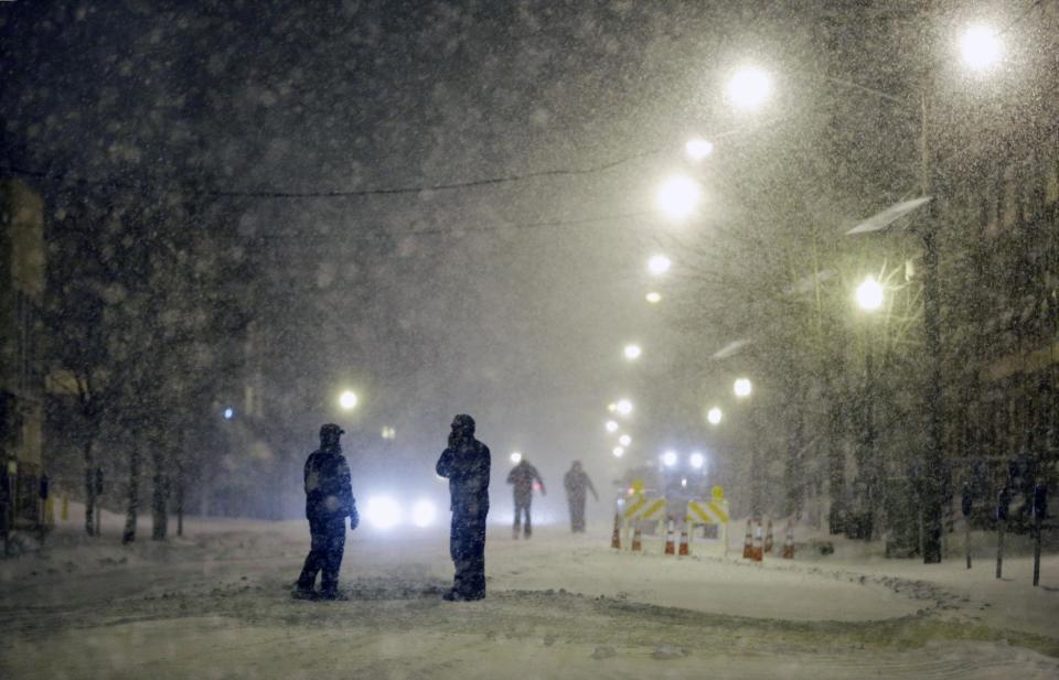 People walk along a street in the snow Tuesday night, Jan. 21, 2014, in Trenton, N.J. A swirling storm with a potential for more than a foot of snow clobbered the mid-Atlantic and the urban Northeast, grounding thousands of flights, closing government offices in the nation's capital and giving students another day off from school. The storm stretched 1,000 miles between Kentucky and Massachusetts.(AP Photo/Mel Evans)