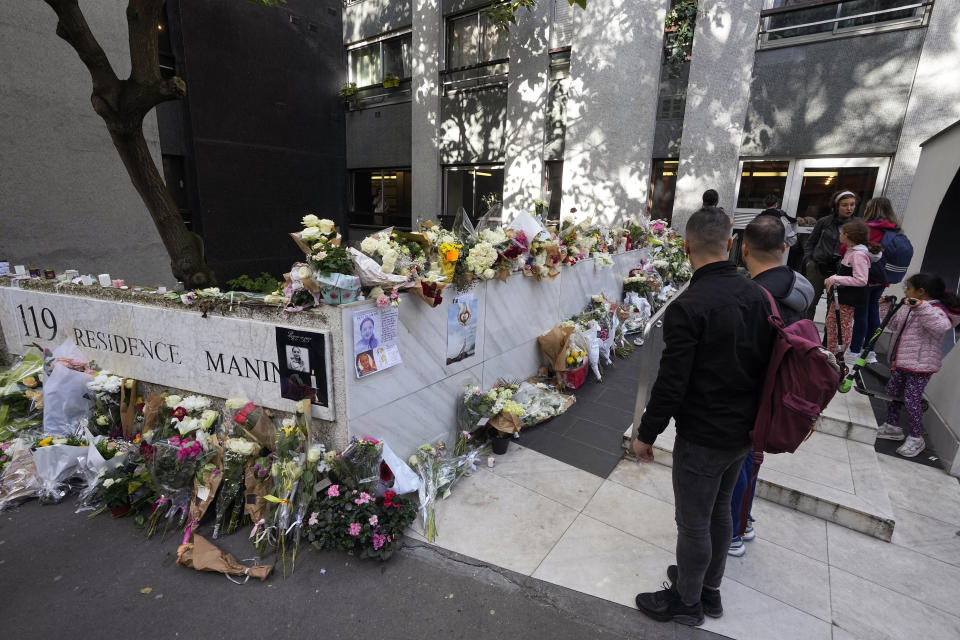 People stand outside the building where the body of 12-year-old schoolgirl was discovered in a trunk, in Paris, Wednesday, Oct. 19, 2022. France has been "profoundly shaken" by the murder of a 12-year-old schoolgirl, whose body was found in a plastic box, dumped in a courtyard of a building in northeastern Paris, the government spokesman Olivier Veran said on Wednesday. (AP Photo/Michel Euler)