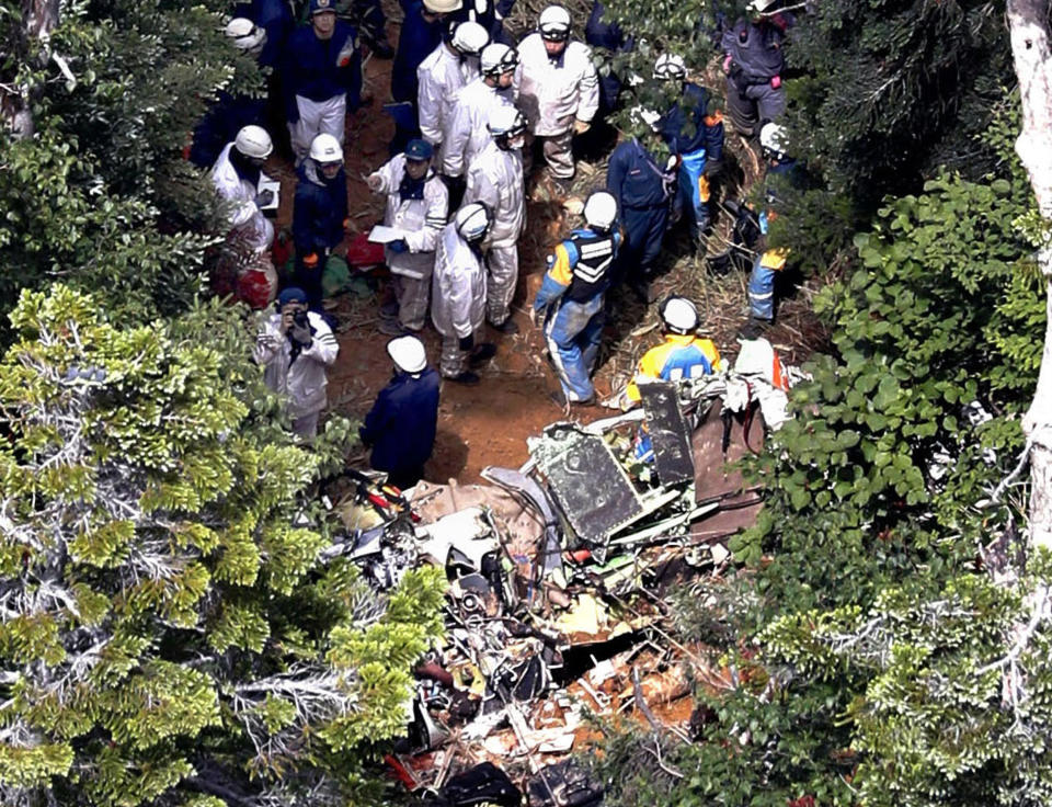 Investigators work near the wreckage of a Japanese search and rescue helicopter that crashed into the central mountains in Nakanojo, Gunma prefecture, northwest of Tokyo Saturday, Aug. 11, 2018. All nine people aboard the helicopter were confirmed dead Saturday, authorities said. (Kyodo News via AP)