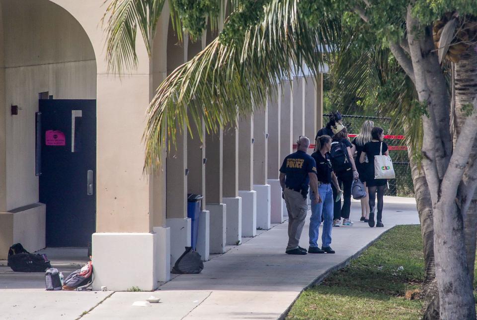 Students and police walk on the campus of Dreyfoos School of the Arts after a city police officer fatally shot a man there Friday afternoon, May 13, 2022. The man had gotten out of a crashed van and run into the school’s theater, where he was fighting with a school police officer when the city officer arrived and shot him.