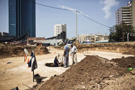 A worker for the Israel Antiquities Authority (IAA) stands in a pit at an archaeological dig in a future construction site in Tel Aviv, where fragments of ancient basins were unearthed, March 29, 2015. REUTERS/Nir Elias