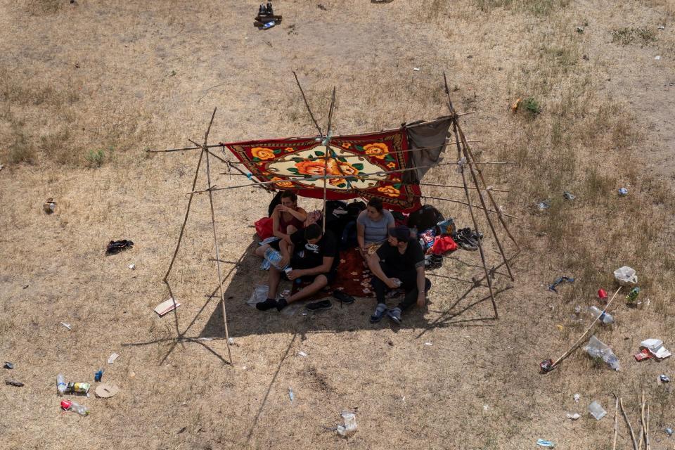 Migrants sheltering under a makeshift tent by Del Rio International Bridge, Texas