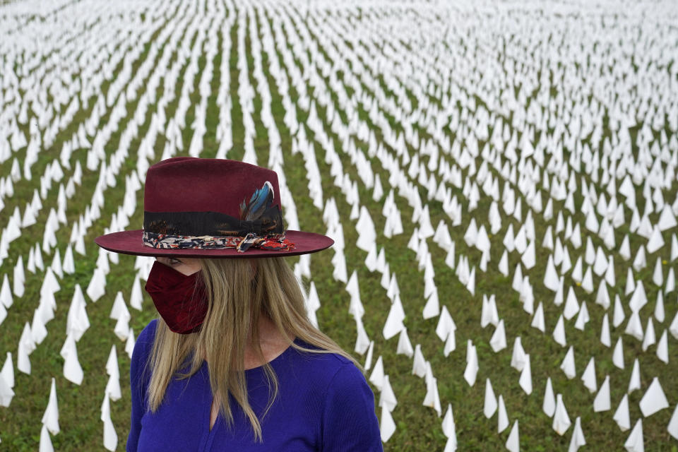 FILE - In this Oct. 27, 2020, file photo, Artist Suzanne Brennan Firstenberg stands among thousands of white flags planted in remembrance of Americans who have died of COVID-19, near Robert F. Kennedy Memorial Stadium in Washington. Firstenberg's temporary art installation, called "In America, How Could This Happen," will include an estimated 240,000 flags when completed. (AP Photo/Patrick Semansky, File)
