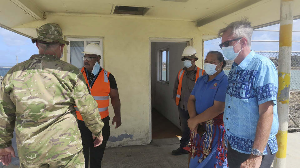 In this photo released by the New Zealand High Commission, Peter Lund, right, New Zealand’s acting high commissioner to Tonga, stands with military personnel at a wharf in Nuku'alofa, Tonga Friday, Jan. 21, 2022, after a New Zealand ship arrived with water and other much-needed aid supplies. (New Zealand High Commission via AP)