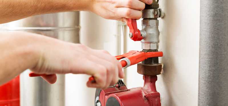 A person is working on pipes with a wrench.