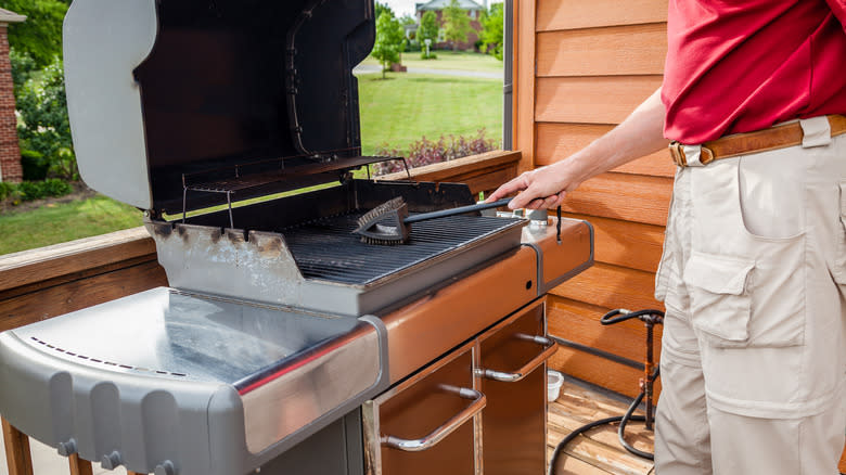 man cleaning grill on patio