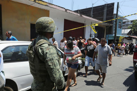 A soldier keeps watch as people leave an area cordoned off by police after a shooting near a Via Crucis representation in Acapulco, Mexico March 30, 2018. REUTERS/Javier Verdin