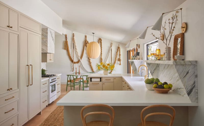 Cream custom cabinets, white countertops, peninsula, with marble backsplash and build in shelves, rope art installation