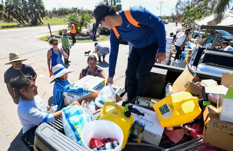 R2C2 volunteer Leonardo Felipe, right, hands supplies, food and water to residents in need at The Palms on Pine Island near Fort Myers, Fla., on Wednesday, Oct. 5, 2022.