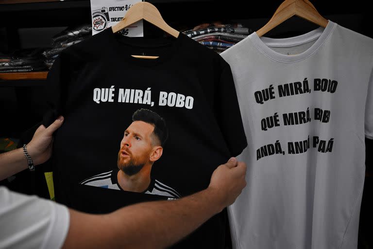 Un hombre sostiene una camiseta con la imagen del delantero argentino Lionel Messi y una frase que dice "Qué mirá, bobo". en una tienda de Buenos Aires