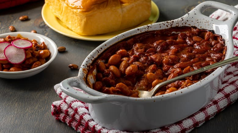 Baked beans in a crock with a spoon