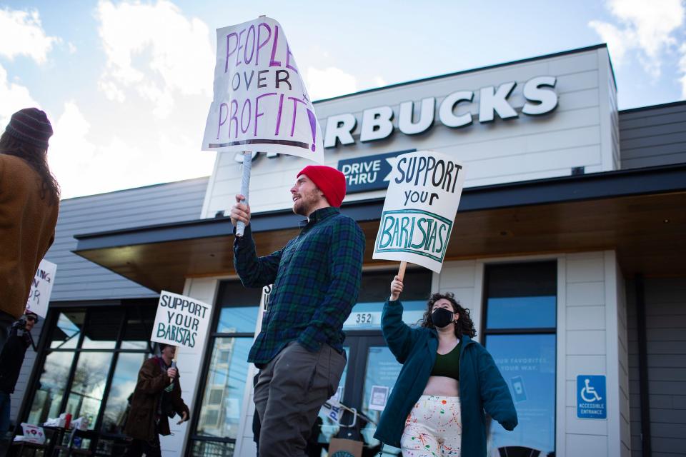 Workers holding signs as part of a Red Cup Rebellion demonstration outside of a Starbucks store.