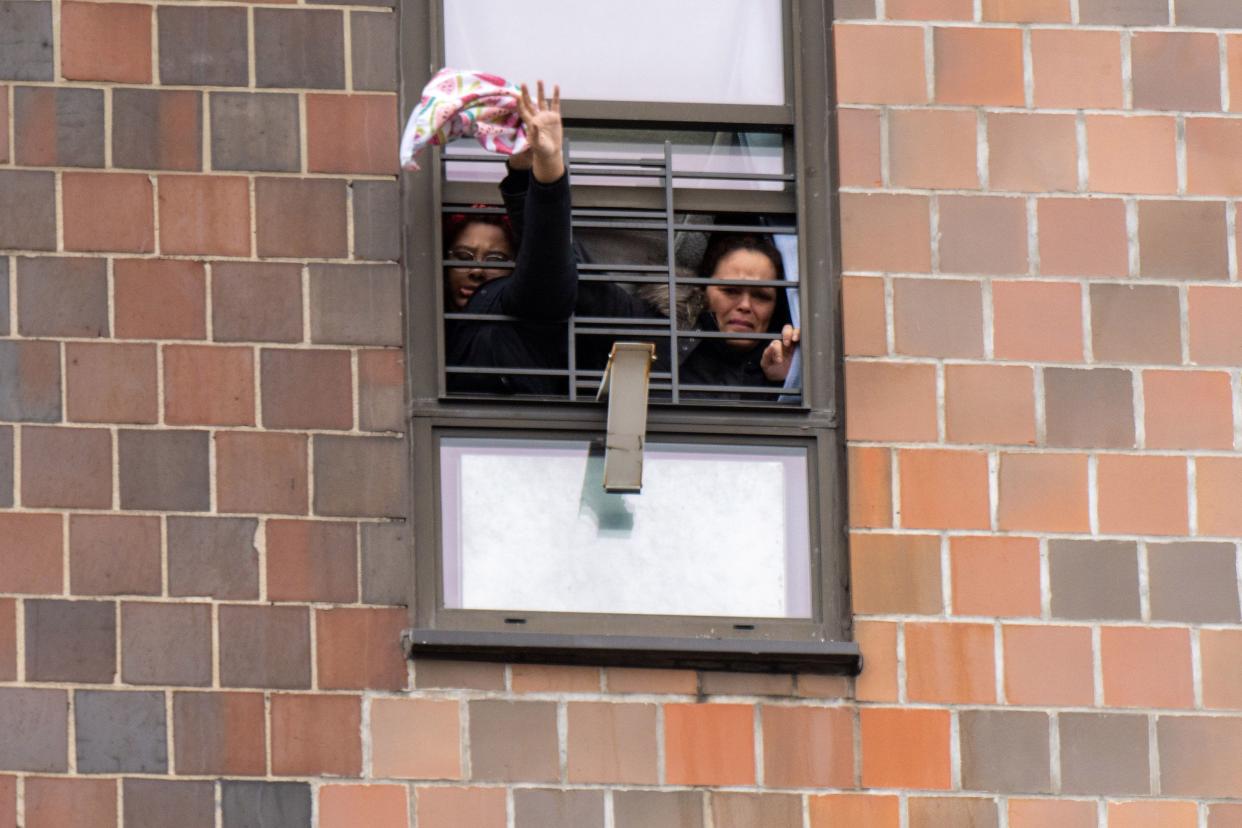 People can be seen yelling and signaling for firefighters from a window during a massive fire in an apartment building in the Bronx on Sunday, Jan. 9, 2022.