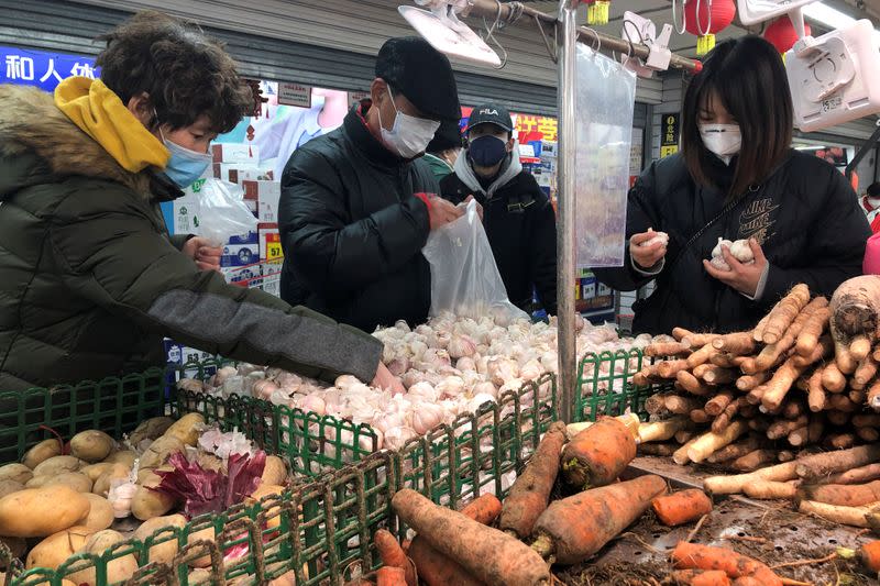 People wearing face masks select vegetables at a supermarket, as the country is hit by an outbreak of the new coronavirus, in Beijing