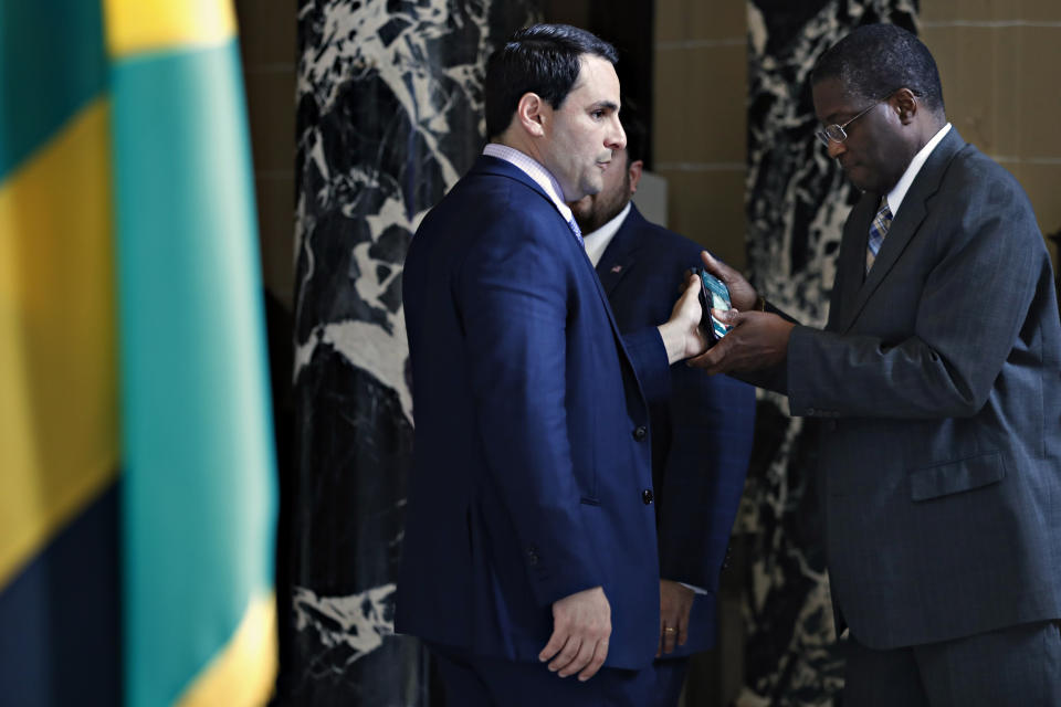 U.S. Permanent Representative to the Organization of American States Carlos Trujillo, left, passes a phone to Jamaican Alternate Representative to the OAS Deon Williams, as they confer minutes before the OAS Permanent Council holds an extraordinary session on Venezuela, Tuesday April 9, 2019, at OAS headquarters in Washington. (AP Photo/Jacquelyn Martin)