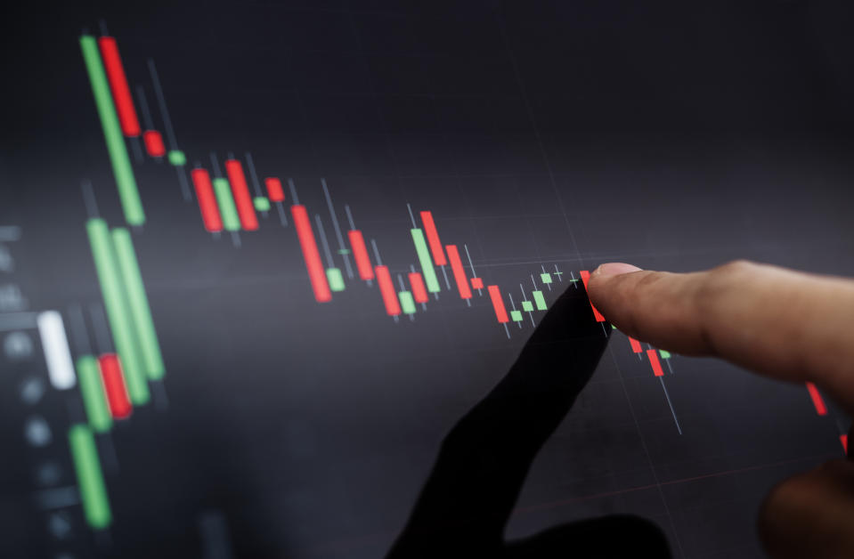 A person places a finger on a declining stock chart