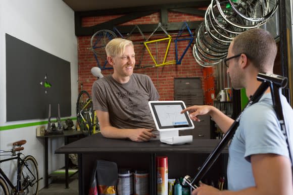 Two men in T-shirts making a Square transaction at a bicycle shop.