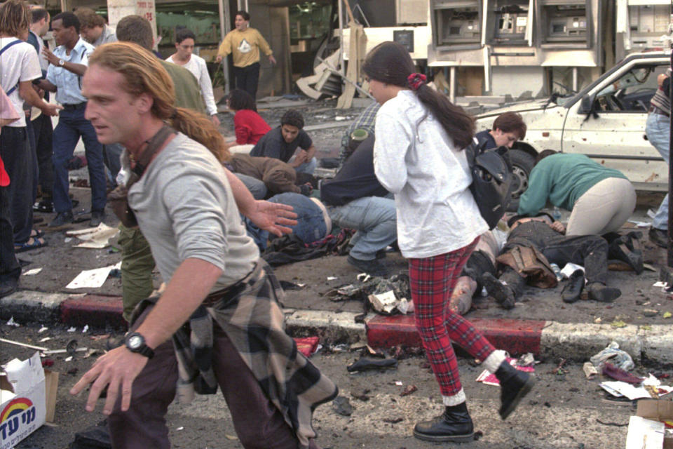 FILE - Israelis run to help medics and bystanders administering medical care to those injured when a suicide bomber blew himself up near a Tel Aviv shopping center Monday March 4, 1996. The Muslim militant group Hamas claimed responsibility for the attack that killed 12 people and injured scores. (AP Photo/Motti Kimchi, File)