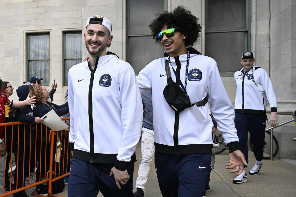 UConn's Alex Karaban, left, and Jayden Ross, right, smile as they board a bus for a parade to celebrate the team's NCAA college basketball championship, Saturday, April 13, 2024, in Hartford, Conn. (AP Photo/Jessica Hill)