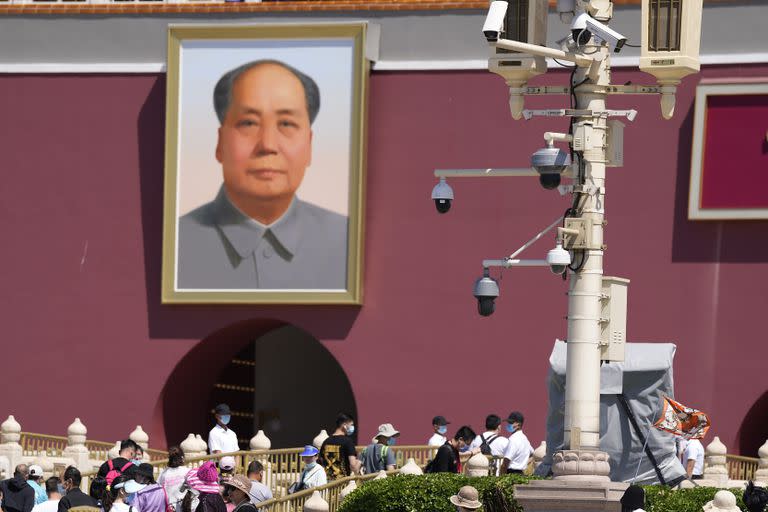 Con varias cámaras de seguridad en un poste, personal de seguridad sin uniforme vigila mientras los turistas visitan la Puerta de Tiananmen en el 32do aniversario de la letal represión de protestas prodemocracia en la plaza, en Beijing, el 4 de junio de 2021